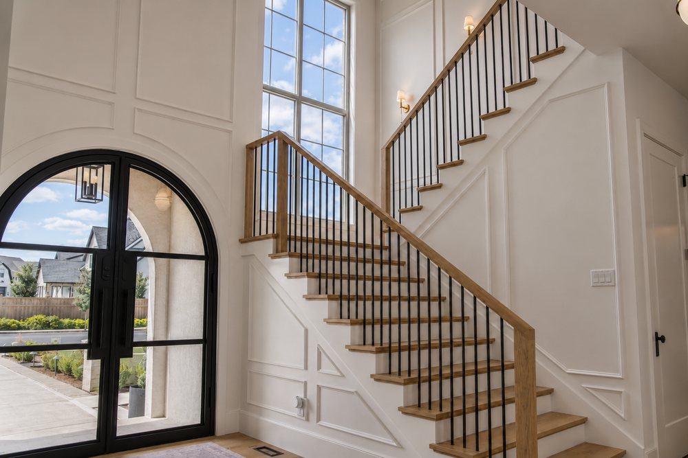A grand entry staircase with wood treads and iron railings