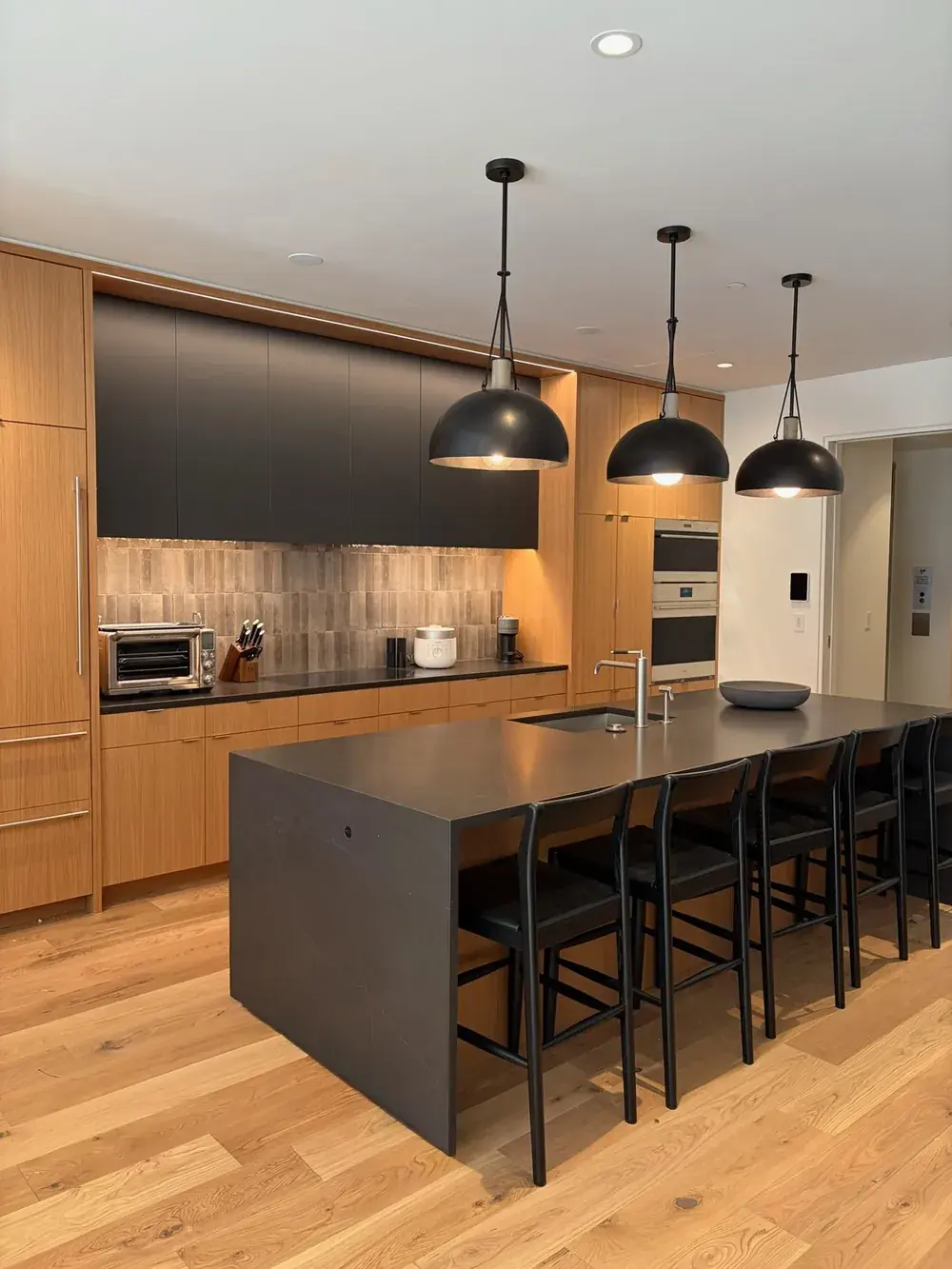 A modern kitchen with warm wood cabinetry and a dark stone island